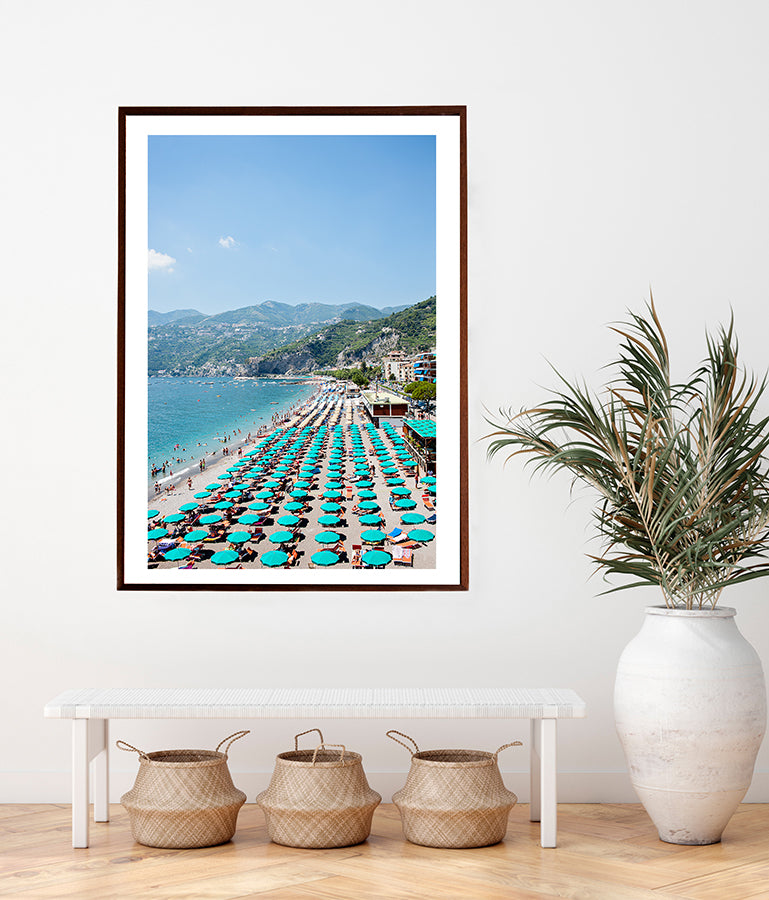 Amalfi Coast photographic print featuring the Amalfi beach in summer with rows and rows of its green umbrellas on the beach, with the blue sea and the green cliffs in the distance. Part of the Into The Blue series by Millie Brown