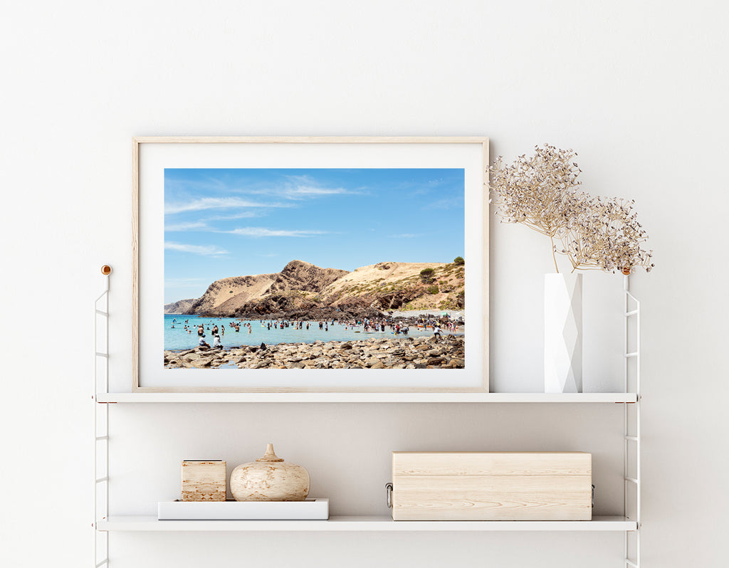 Beach wall art featuring summer day on an Australian beach, beautiful rolling hills in the background and beachgoers enjoying the water in the foreground