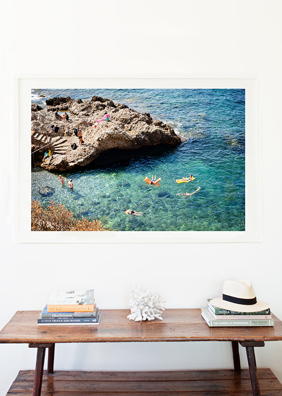 Cote d'azur wall art prints featuring the French Riviera and a small beautiful swimming cove surrounded by rocks and showing people swimming in the blue mediterranean sea, shot from above by travel photographer Millie Brown