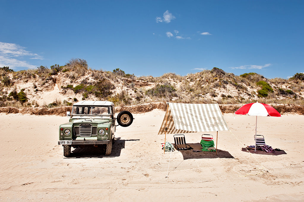 Photographic beach wall art print of long beach robe, featuring a land rover, beach umbrellas and chairs , with the beautiful sand dunes behind, available in small to extra large  artwork sizes, part of the Salty Days collection by Millie Brown