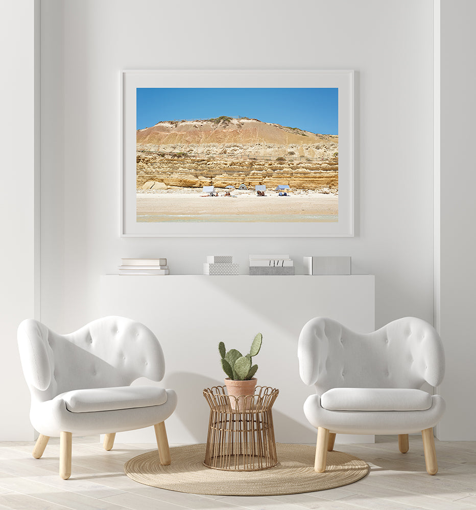 Australian beach wall art featuring Port Willunga beach with the white sand and beachgoers under stripped beach tents with the towering limestone cliffs behind them and a big blue sky