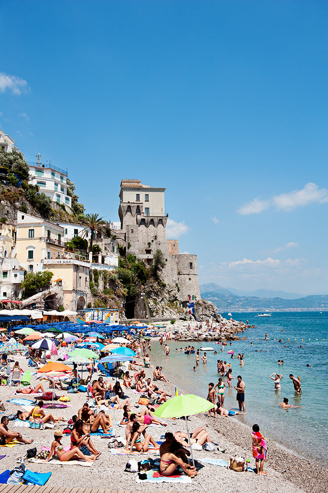 Amalfi coast photographic wall art print of Cetara beach on the Amalfi Coast with colourful beach umbrellas and beachgoers on the shore and in the sea by photographer Millie Brown