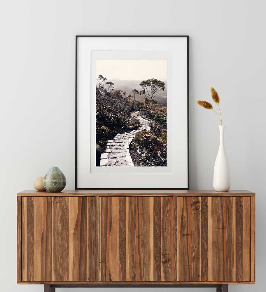 Cradle Mountain prints featuring the beauty of the Tasmanian wilderness of Cradle Mountain National Park, this print shows a snowy trail leading down a mountain surrounded by snow capped bushland by photographer Millie Brown