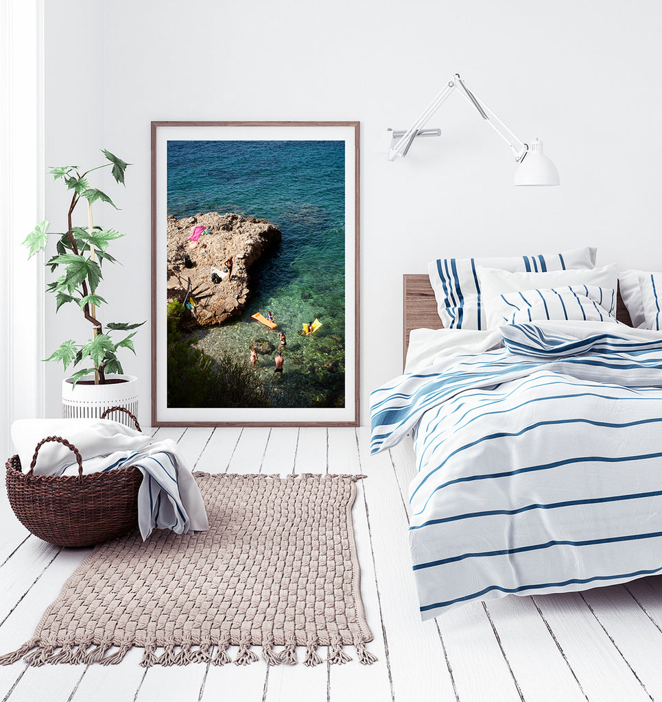 French Riviera beach print limited edition shot from above with swimmers in the sea and a rocky outcrop with beach towels and a swimmer