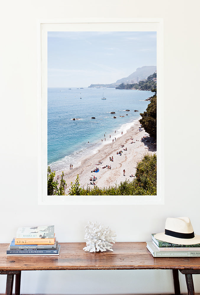 French Riviera Photographic Print featuring Plage du Buse with beachgoers on the beach and in the water shot from above and Monaco in the distance by Millie Brown